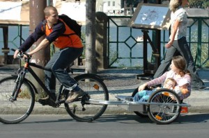 Otec veze na vozíku maminku, která drží malé dítě...